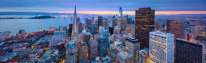 view from atop tall building in bay area looking down at other buildings and the bay