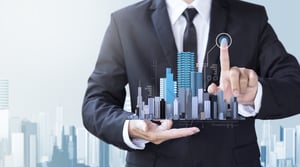 man in suit holding scale model of city skyscrapers