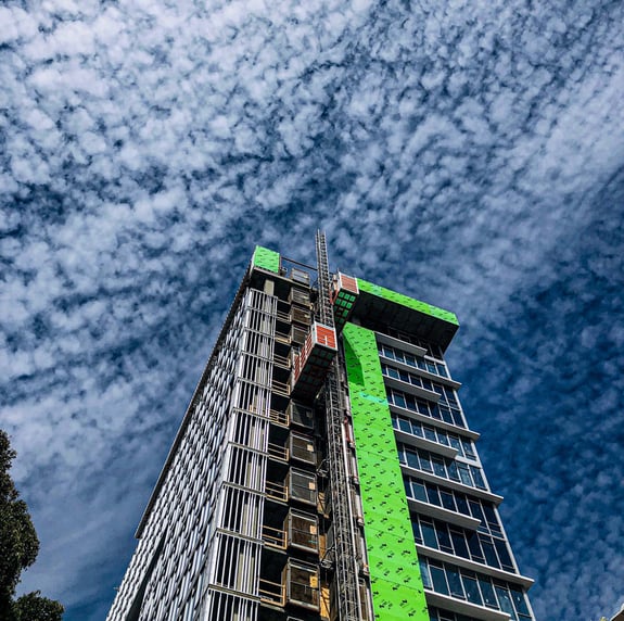 looking up at partly cloudy sky next to building under construction
