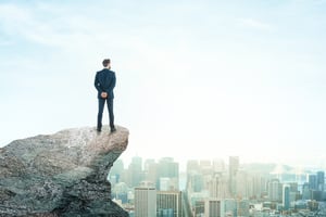 man on cliff looking out at city